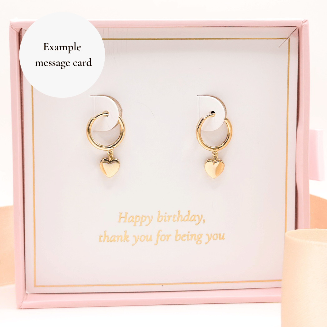 Gold-tone heart huggie hoop earrings with heart charms in a gift box.