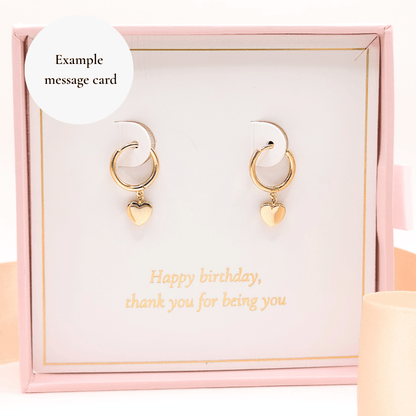Gold-tone heart huggie hoop earrings with heart charms in a gift box.