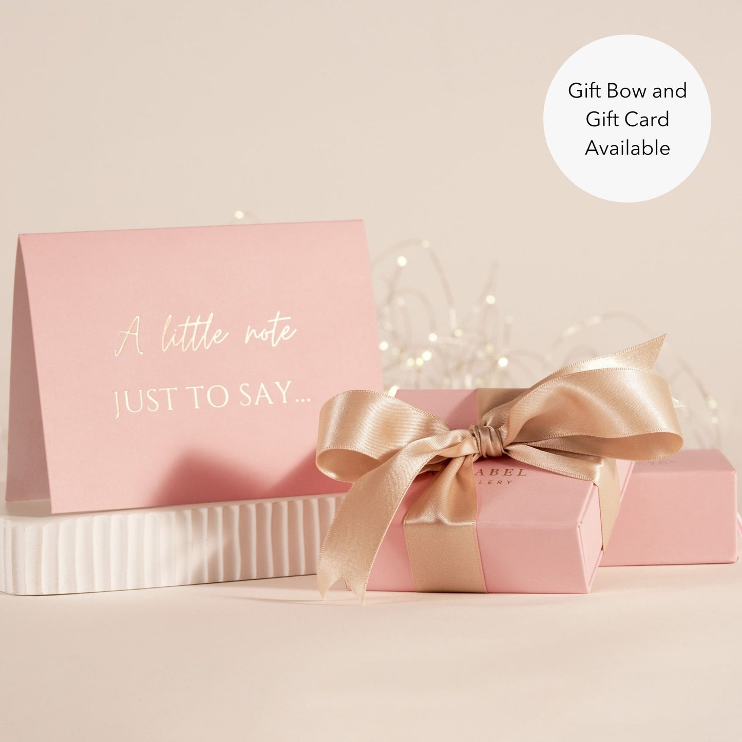 Pink gift box with a bow and pink card on a beige background