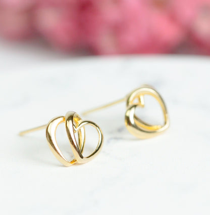 Gold-tone heart stud earrings with interlocking hearts and visible post
