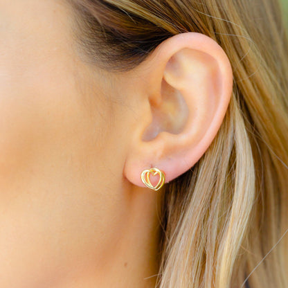 Heart stud earrings on ear, gold-tone double heart design with post backs