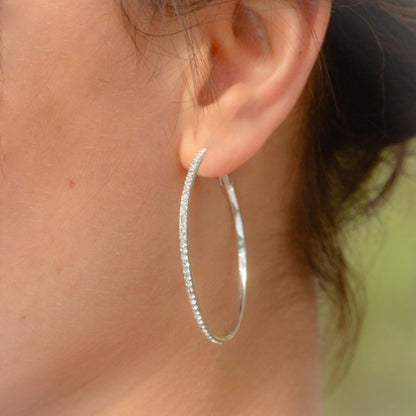 Silver hoop earrings with diamond pavé stones, worn on ear