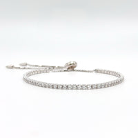 Adjustable silver tennis bracelet with pavé stones and prong clasp, laid flat
