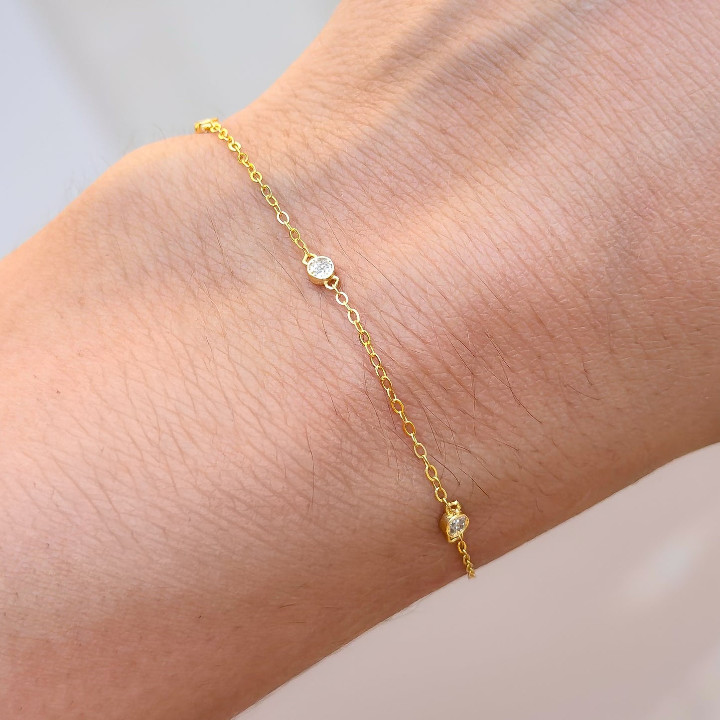 Gold-tone CZ trio bracelet with three small round stones on a fine chain