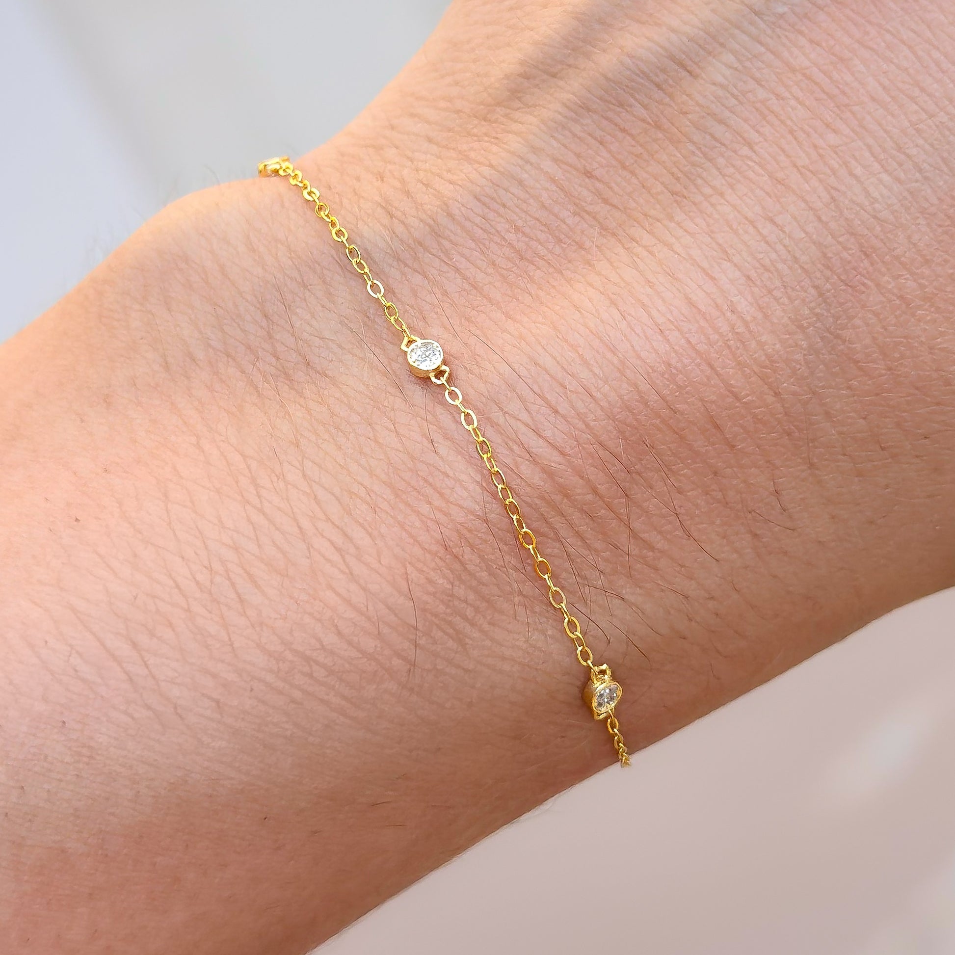 Gold-tone CZ trio bracelet with three small round stones on a fine chain
