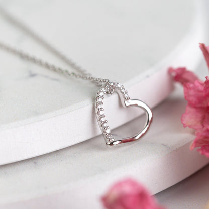 Silver open heart pendant necklace with clear stone border, close-up view