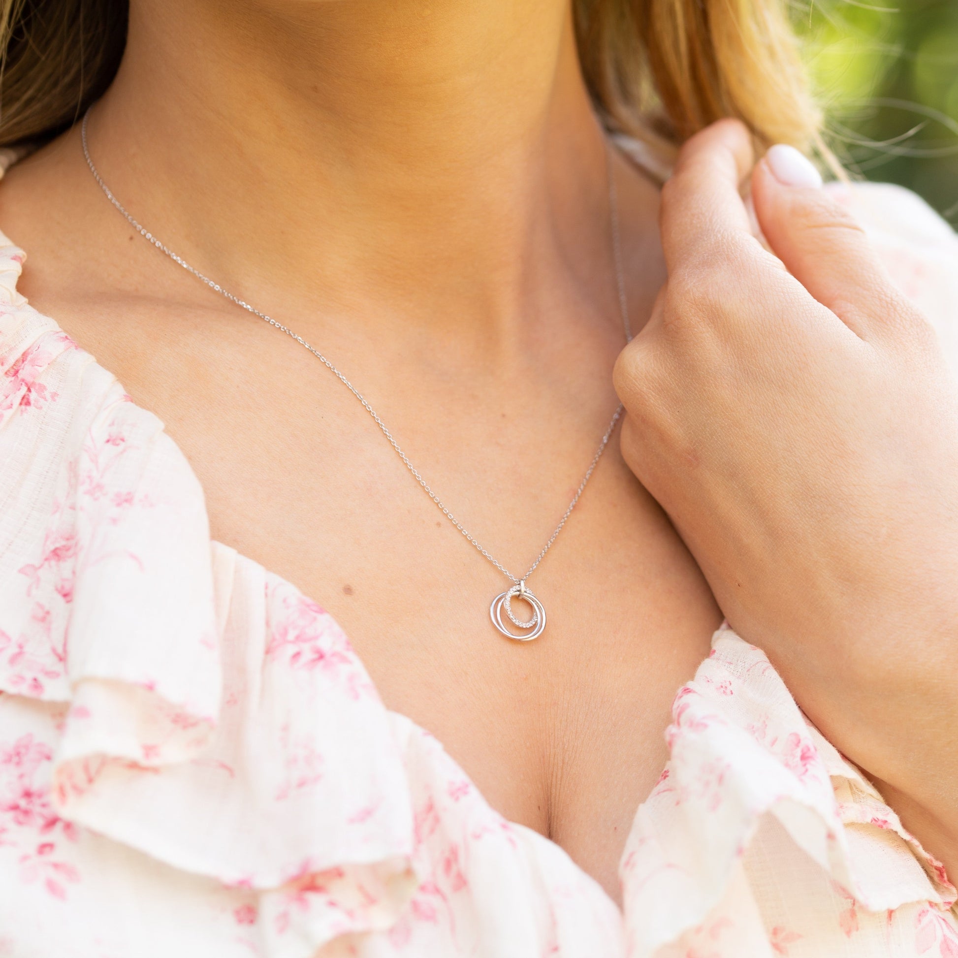 Silver ring pendant necklace worn with a floral pink dress