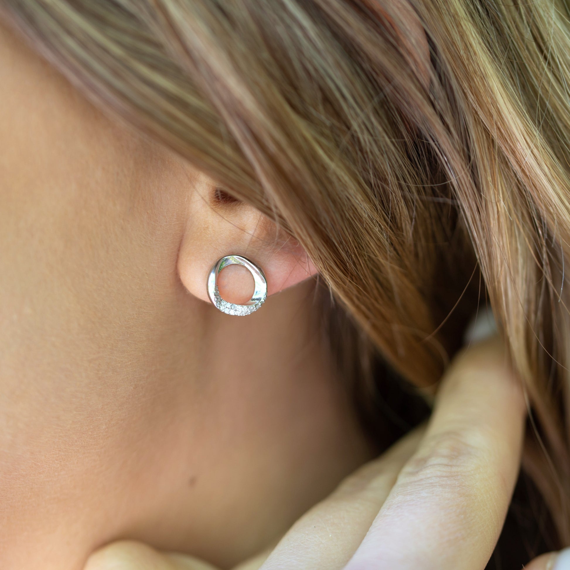 Close-up of a person wearing a silver hoop earring with blurred background