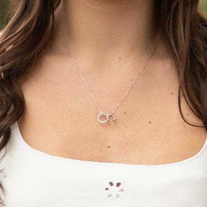 Silver mother-daughter necklace pendant on neckline, linked circles with stones