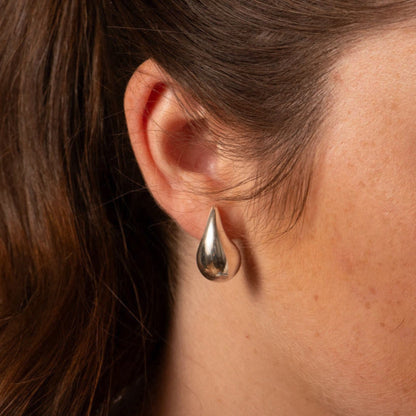 Silver teardrop statement earrings with polished drop shape on ear