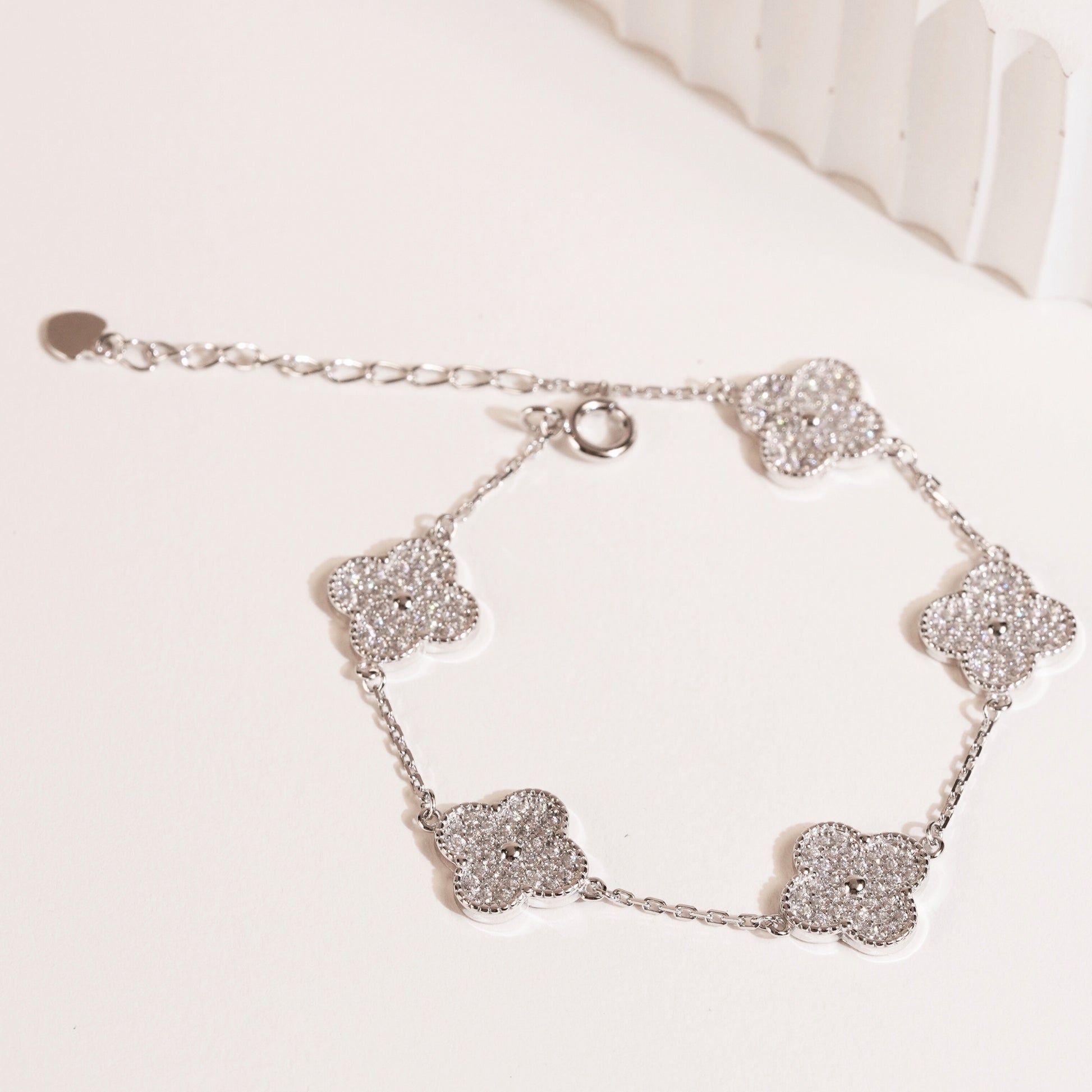 Silver bracelet with clover-shaped charms on a white background