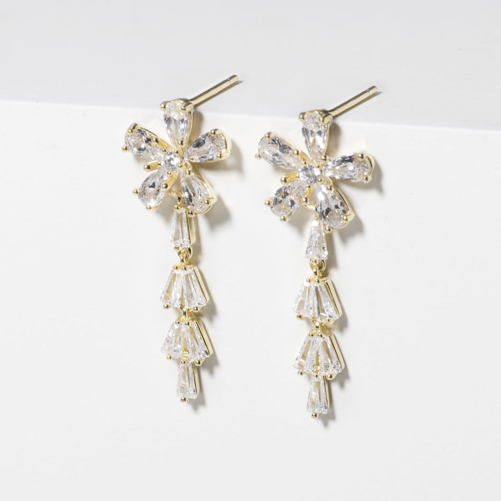 Pair of gold and crystal earrings on a white surface
