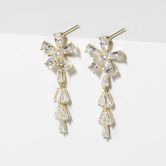 Pair of gold and crystal earrings on a white surface