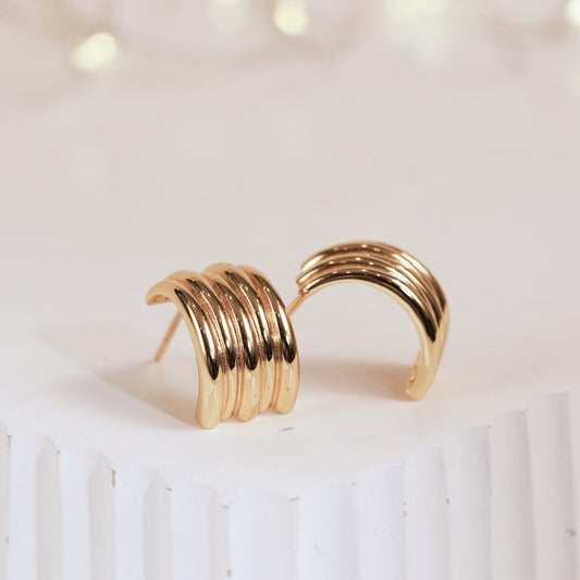 Gold hoop earrings on a white surface with a soft focus background