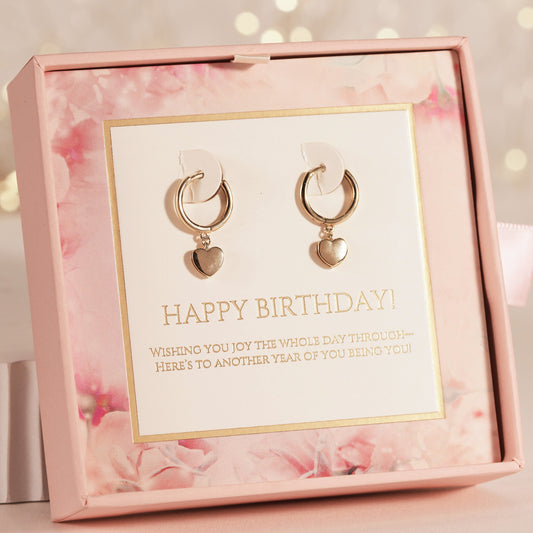 Gold hoop earrings with heart charms in a pink floral box with a birthday message.