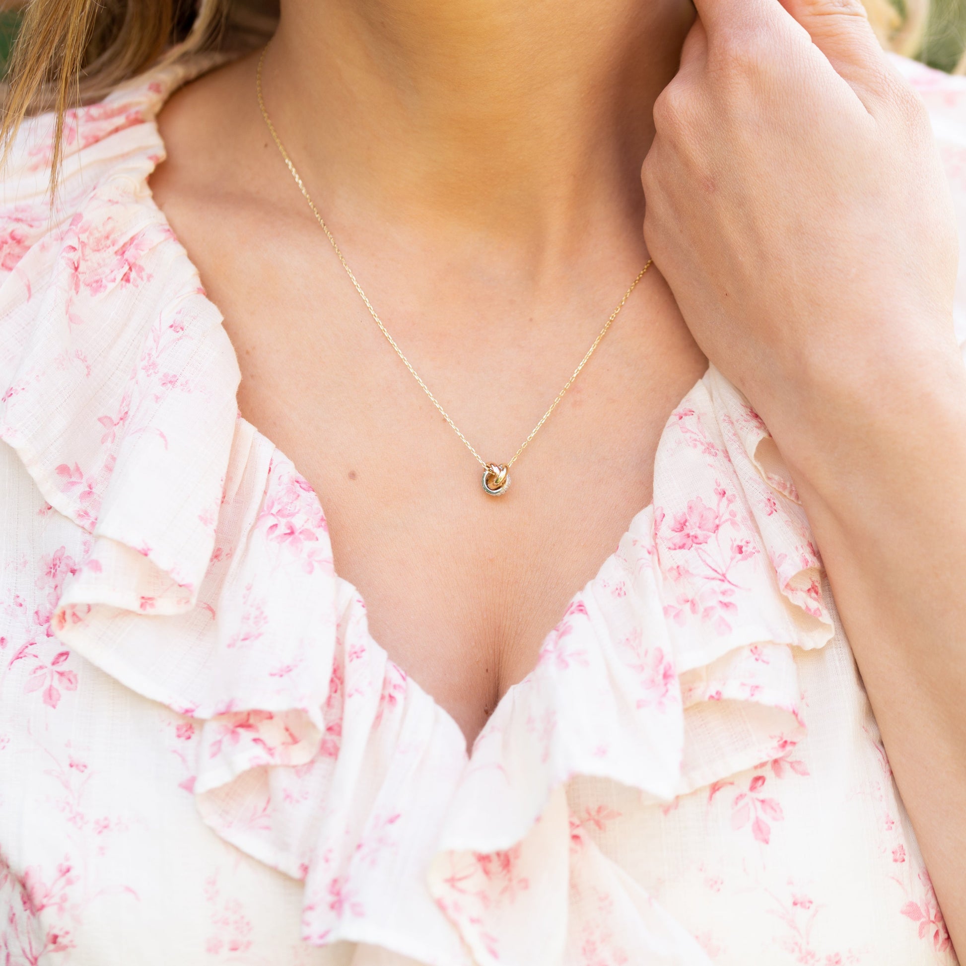 Person wearing a floral dress with a gold necklace