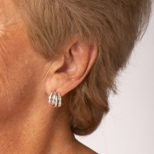 Woman with short blonde hair wearing earrings against a plain background