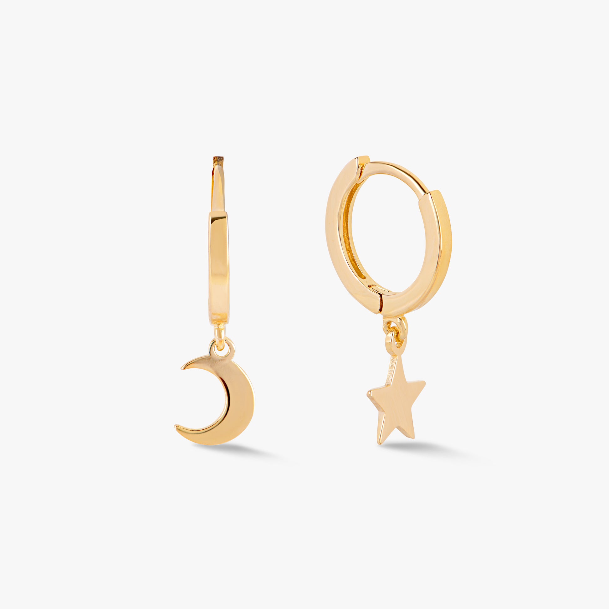 A pair of mis-matched sterling silver huggie hoop earrings, one shaped like a crescent moon and the other like a star, on a white background.