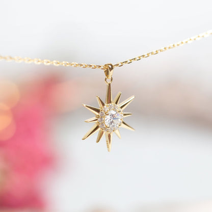 Gold starburst pendant necklace with crystal center and star ray details
