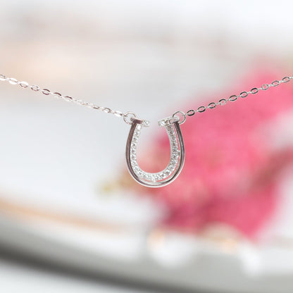 Silver horseshoe pendant necklace on a chain with sparkling side stones