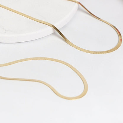 Gold flat snake chain bracelet laid in curved loops