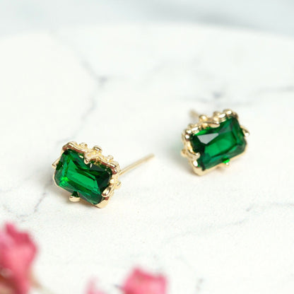 Pair of gold emerald stud earrings with square green gemstones and decorative bezels