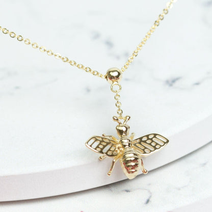 Gold bee pendant necklace with striped bee body and detailed wings