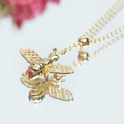 Gold bee pendant necklace with detailed wings and striped body on a chain