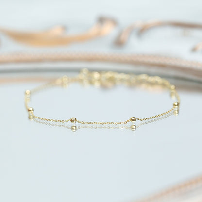 Gold satellite chain bracelet with round beads, laid flat