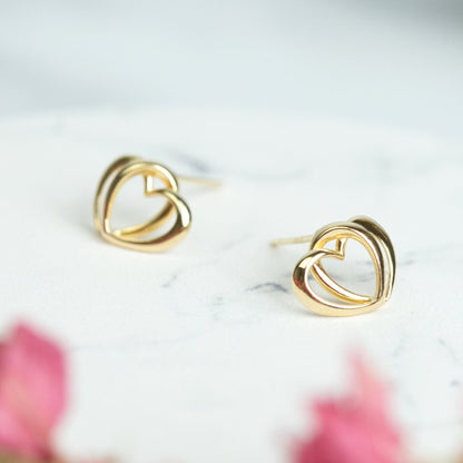 Gold-tone heart stud earrings, side view of interlocking heart fronts
