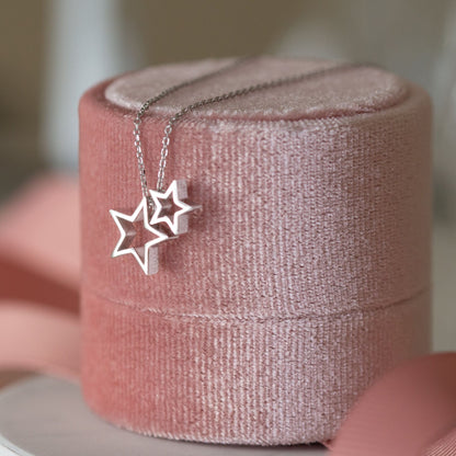 Silver star necklace with two star pendants on a link chain, shown on a box