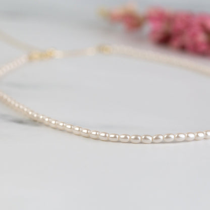 White pearl choker necklace with evenly spaced round pearls, close-up side view