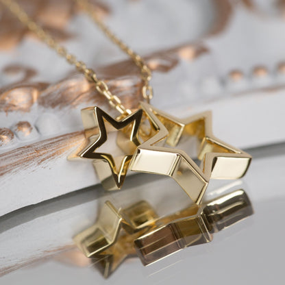 Gold star necklace with two star pendants on a link chain, close-up