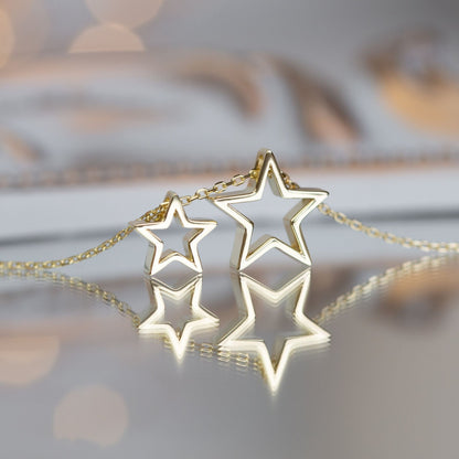 Gold star necklace with two star pendants and a chain, shown close-up