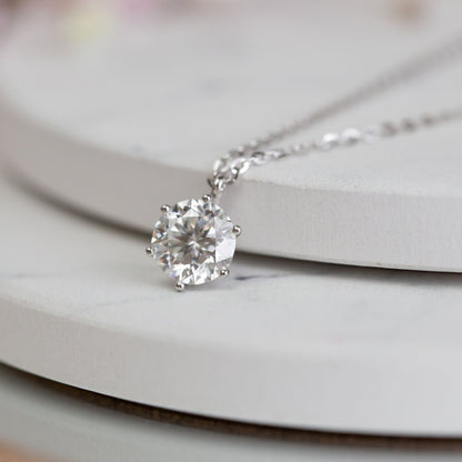 Moissanite diamond pendant close-up, round center stone with metal prongs