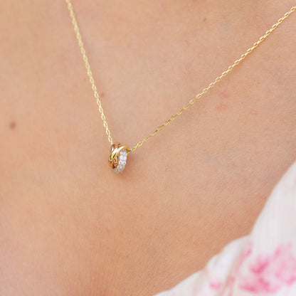 Gold knot necklace pendant on skin with oval pavé sparkle