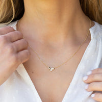 Gold firefly pendant necklace with butterfly-style wings and clear center stone