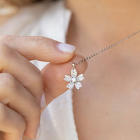 Hand holding sterling silver flower drop earring with diamond-like starburst charm