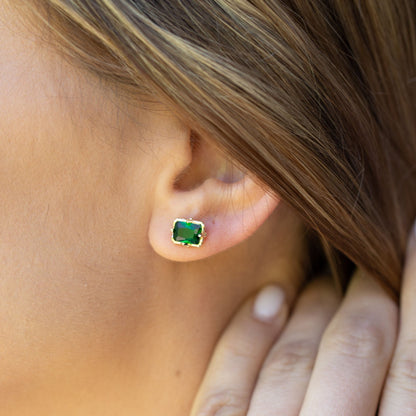 Gold emerald stud earring with square green gemstone in gold bezel, on ear