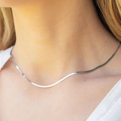 Snake chain necklace in silver tone, curved links resting at collarbone