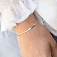 Silver flat snake chain bracelet on wrist, slim curved band