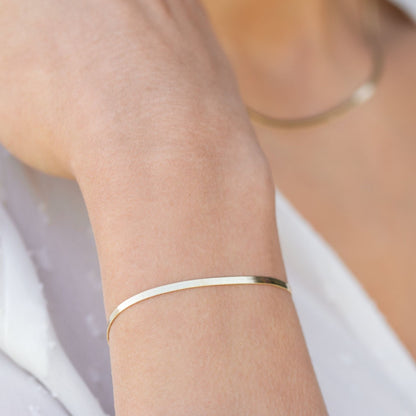Snake chain necklace in silver tone, worn as a thin bracelet on wrist