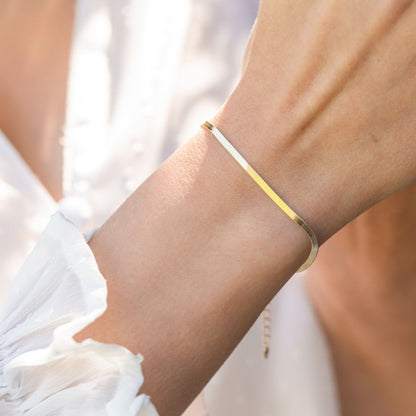 Two-tone flat snake chain bracelet on wrist with slim metal bands