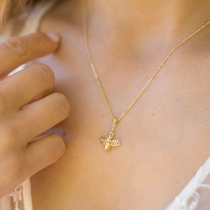Gold bee charm necklace with small pendant centered on a fine chain