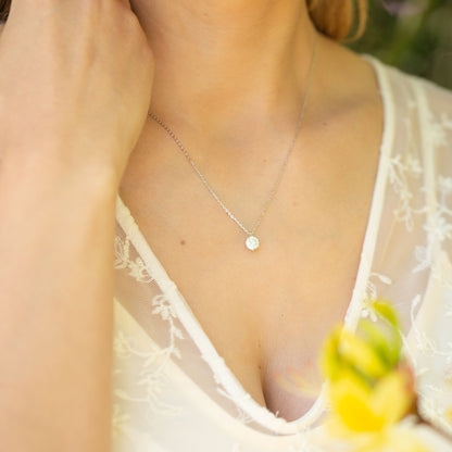 Moissanite diamond pendant on silver chain worn at chest, round prong-set stone