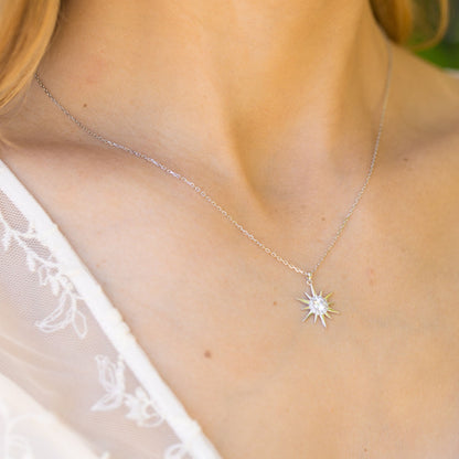 Silver starburst pendant necklace with crystal sunburst charm on a fine chain