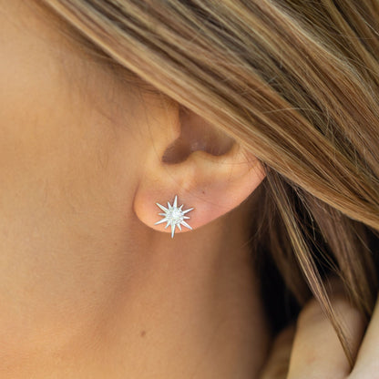 Silver starburst crystal stud earrings on wearer’s ears