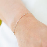 Silver satellite chain bracelet with small round beads, worn on wrist