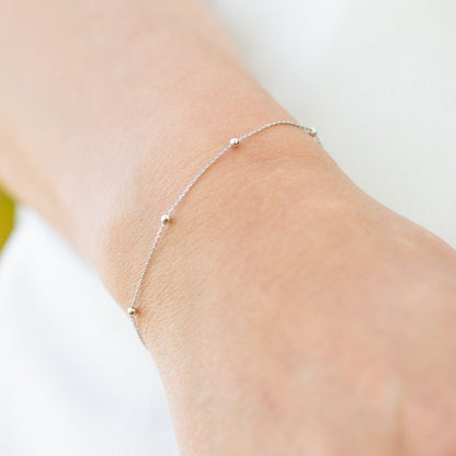 Silver satellite chain bracelet with small round beads, worn on wrist